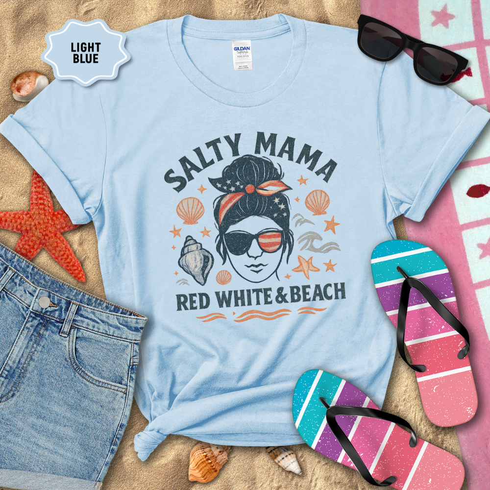 Light blue t-shirt with 'Salty Mama Red White & Beach' design on a sandy background with beach accessories.