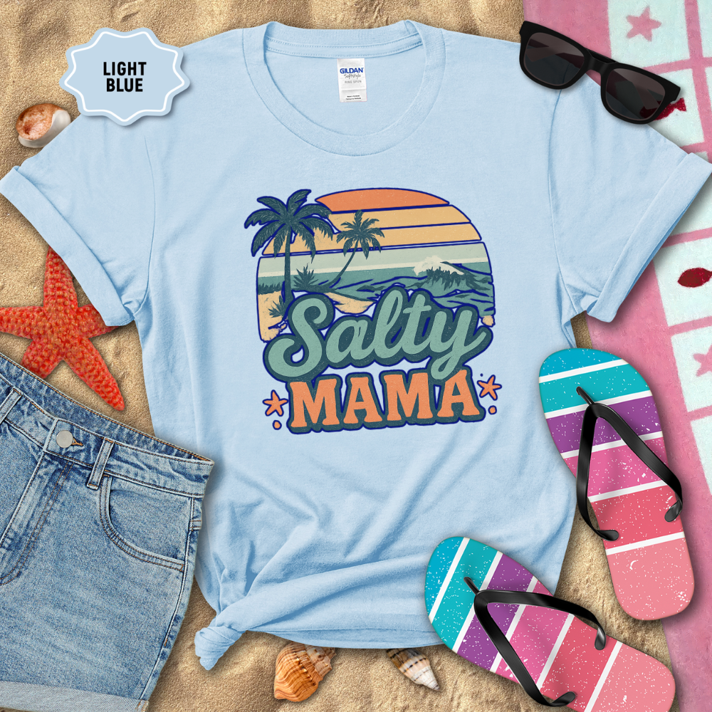 Light blue t-shirt with 'Salty Mama' design on a sandy background with beach accessories.
