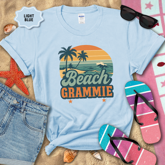 Light blue t-shirt with 'Beach Grammie' design on sand with beach-themed accessories.