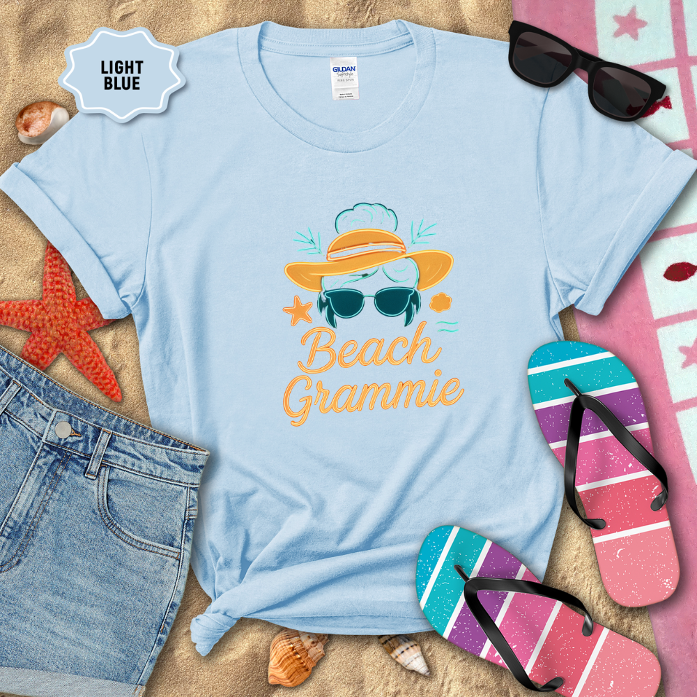 Light blue t-shirt with 'Beach Grammie' design on sand with beach accessories.