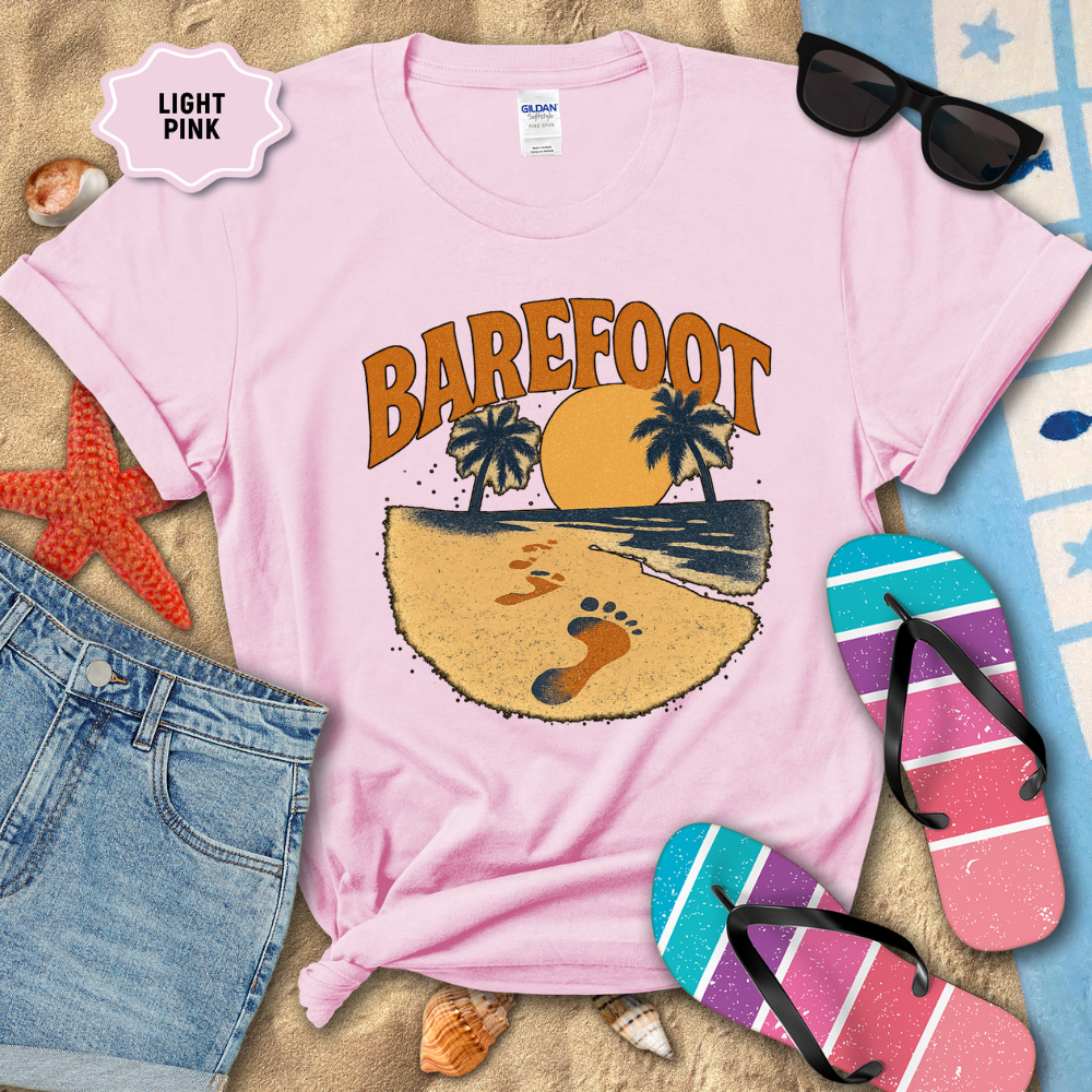 Light pink t-shirt with 'Barefoot' design on a beach-themed background with sunglasses, flip-flops, and denim shorts.