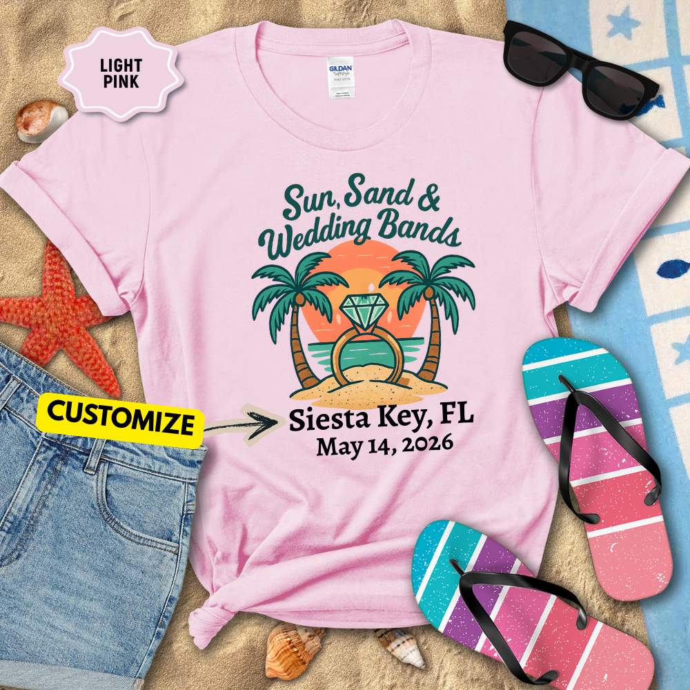Light pink t-shirt with beach-themed design and customizable text, surrounded by beach accessories.