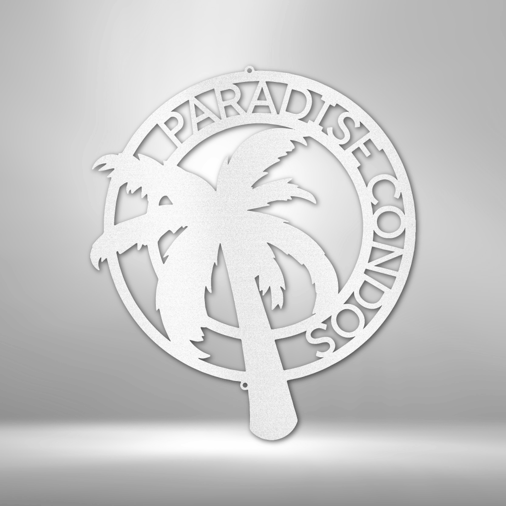 Decorative metal wall art with palm trees and 'Paradise Found' text on a gray background