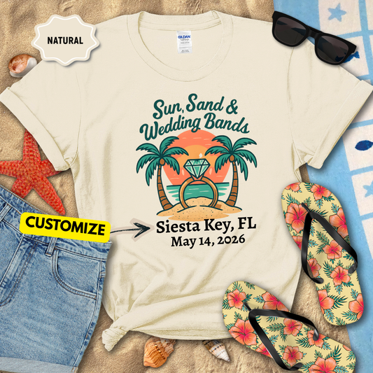 Beige t-shirt with 'Sun, Sand & Wedding Bands' design on a beach-themed background with flip-flops and sunglasses.