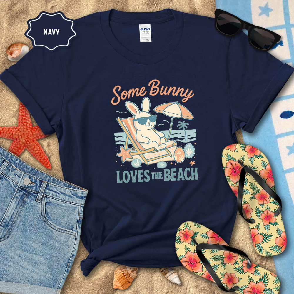 Navy t-shirt with beach-themed design featuring a bunny, sunglasses, and flip-flops on sand.