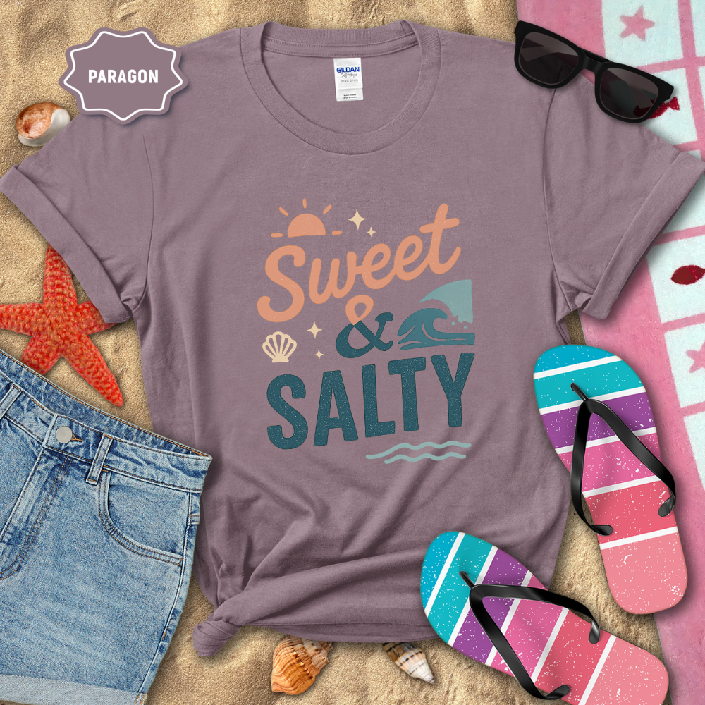 Purple t-shirt with 'Sweet & Salty' design on a sandy background with beach accessories.