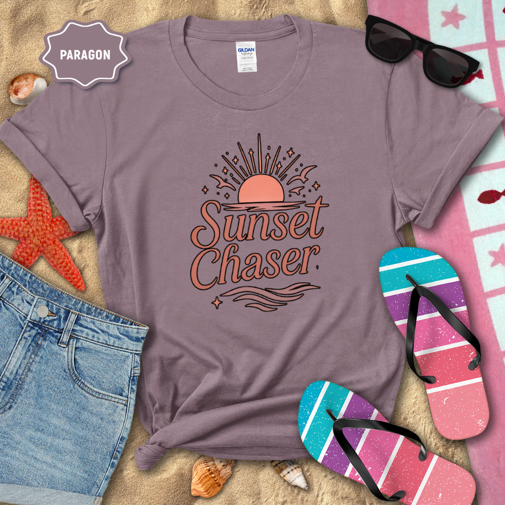 Purple t-shirt with 'Sunset Chaser' design on a sandy background with beach accessories.