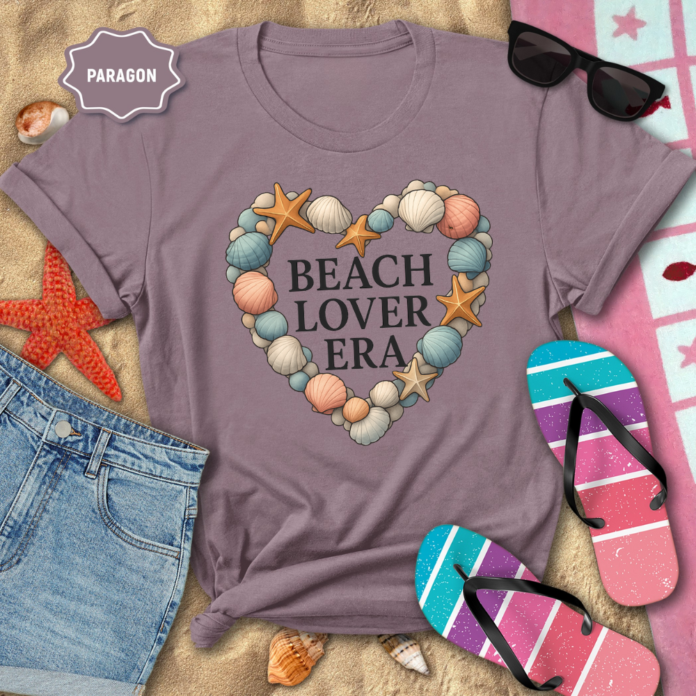 Purple t-shirt with 'Beach Lover Era' design on a sandy background with beach accessories.