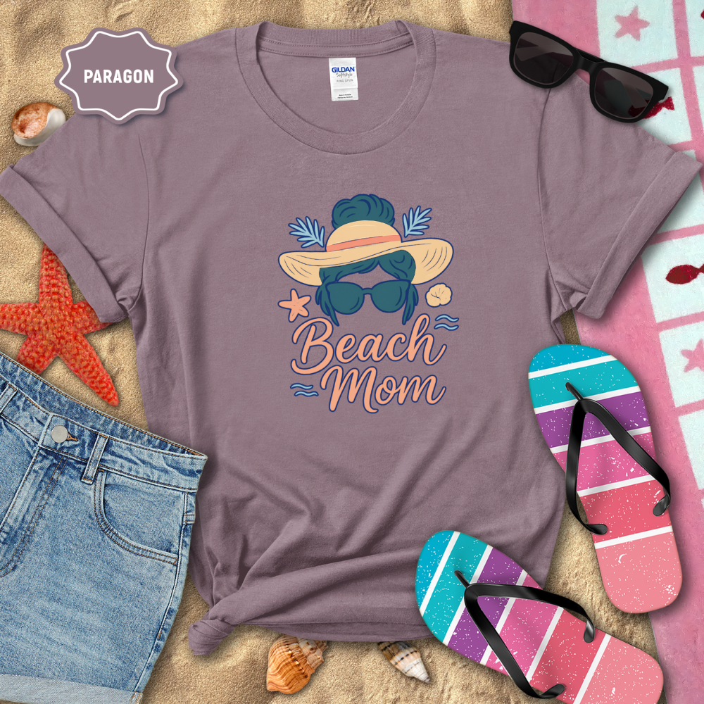 Purple t-shirt with 'Beach Mom' design on a sandy background with beach accessories.