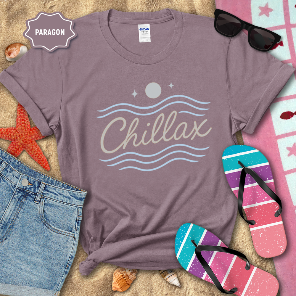 Purple t-shirt with 'Chillax' design on a sandy background with beach accessories.