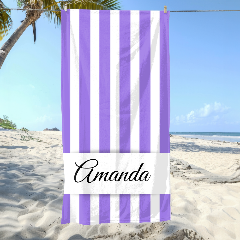 Beach towel with purple and white stripes and the name 'Amanda' on a sandy beach with palm trees.