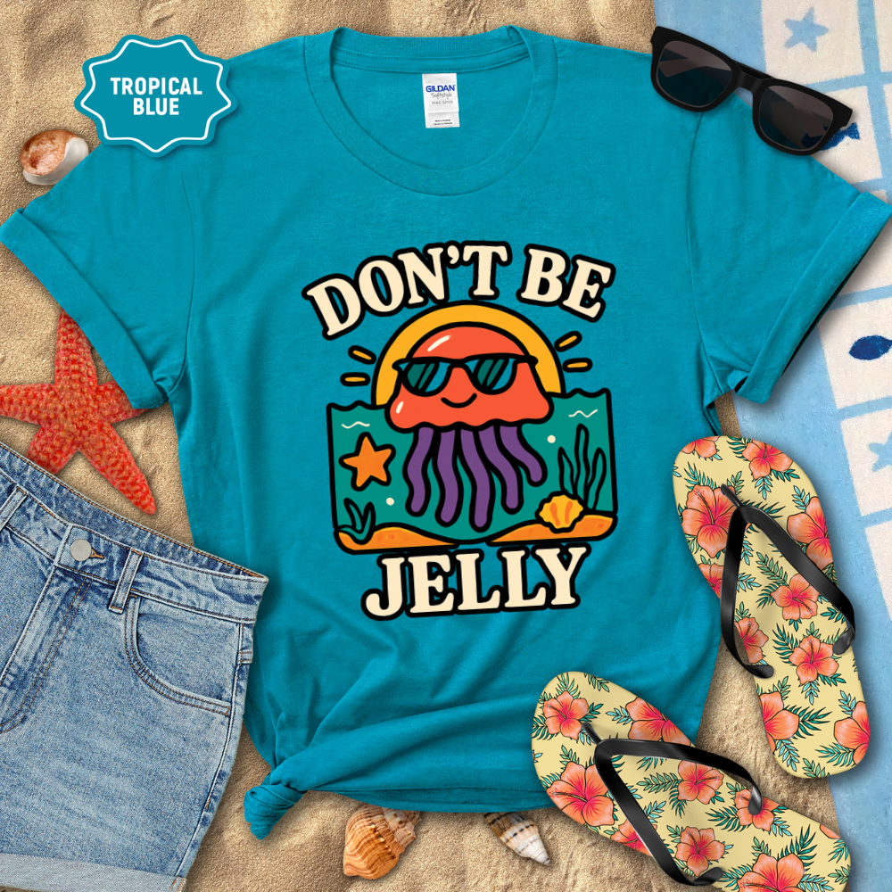 Blue t-shirt with 'Don't Be Jelly' design on a beach setting with sunglasses, flip-flops, and starfish.