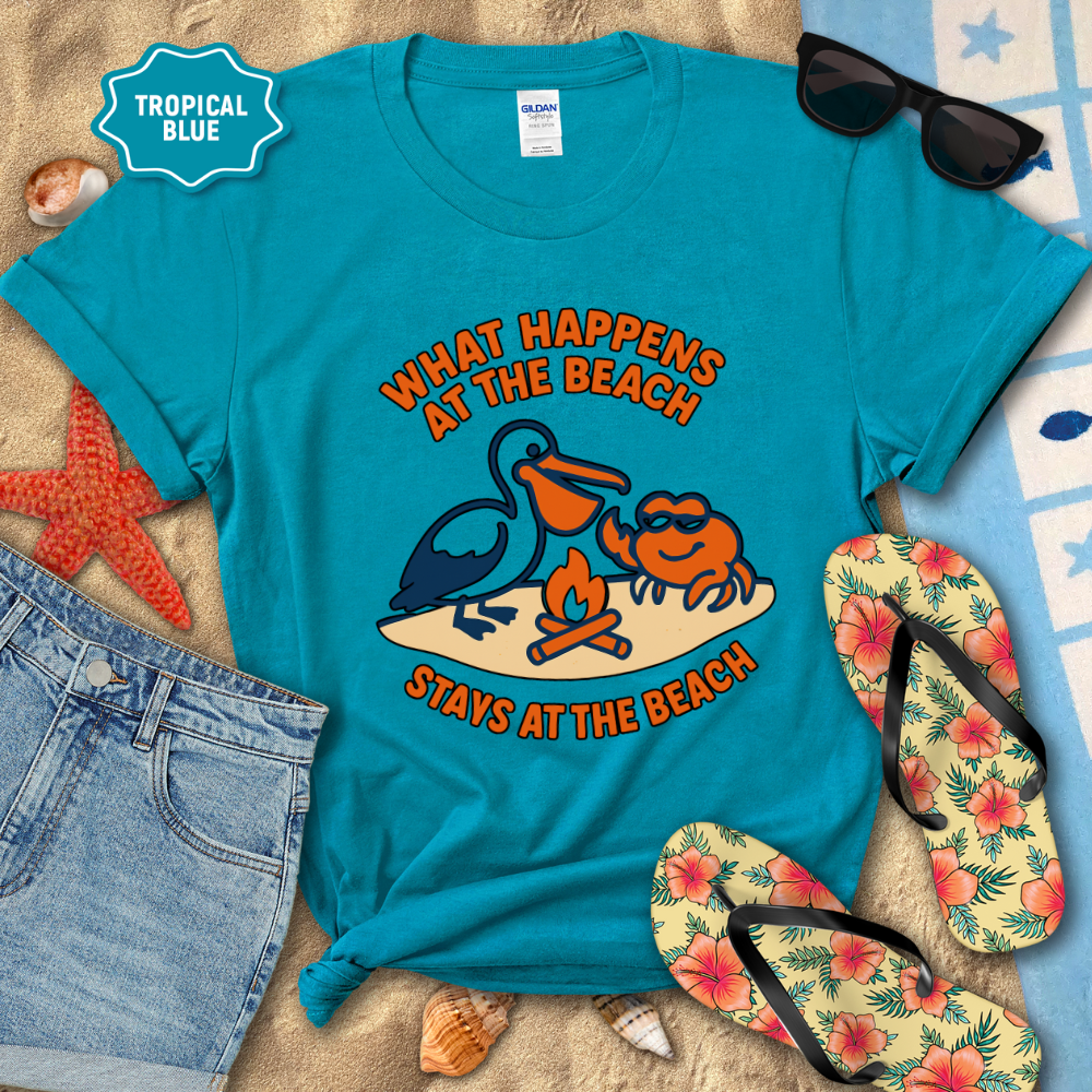 Blue t-shirt with beach-themed design and accessories on a sandy background
