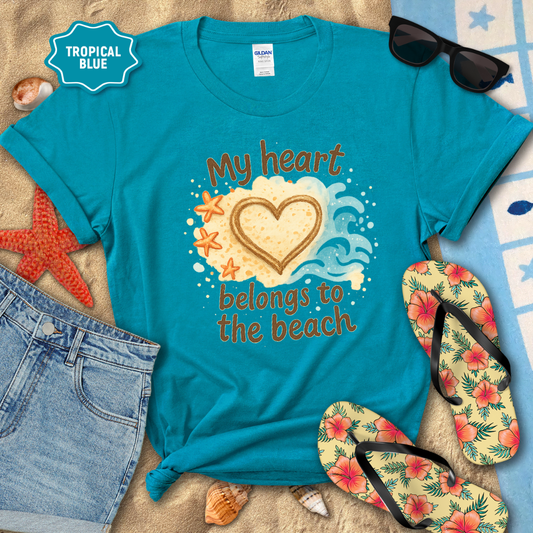 Turquoise t-shirt with 'My heart belongs to the beach' design on a sandy background with flip-flops and sunglasses.