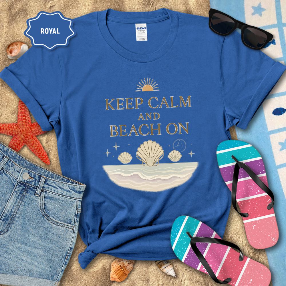 Blue t-shirt with 'Keep Calm and Beach On' design on a sandy surface with beach accessories.