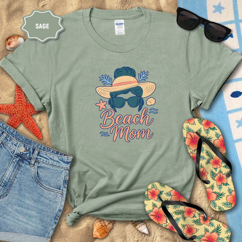Sage green t-shirt with 'Beach Mom' design on a sandy background with flip-flops and sunglasses.