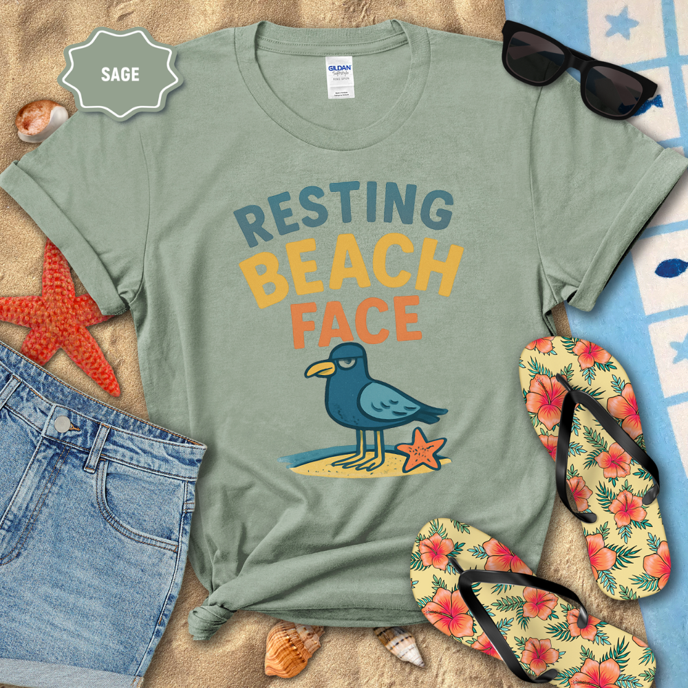 Sage green t-shirt with 'Resting Beach Face' design on a beach-themed background