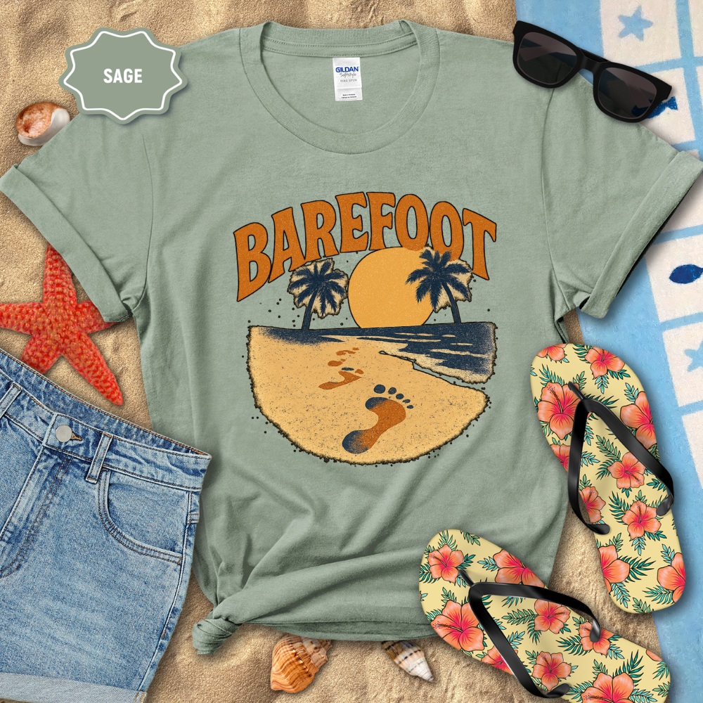 Sage green t-shirt with 'Barefoot' graphic design on a beach-themed background with sunglasses, flip-flops, and starfish.