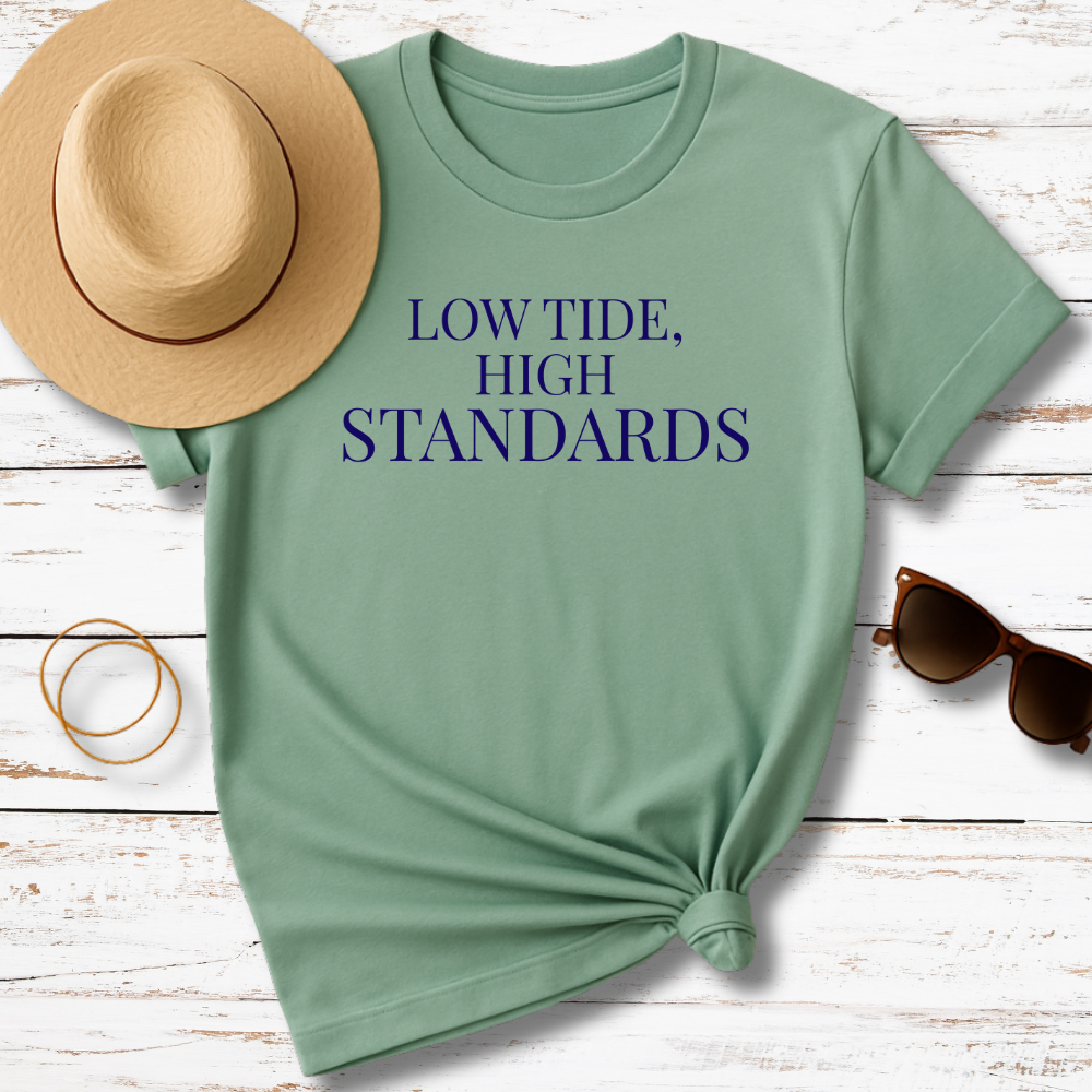 Green t-shirt with 'THE TIDE PROVIDES' text, accompanied by a hat, sunglasses, and bracelet on a wooden surface.
