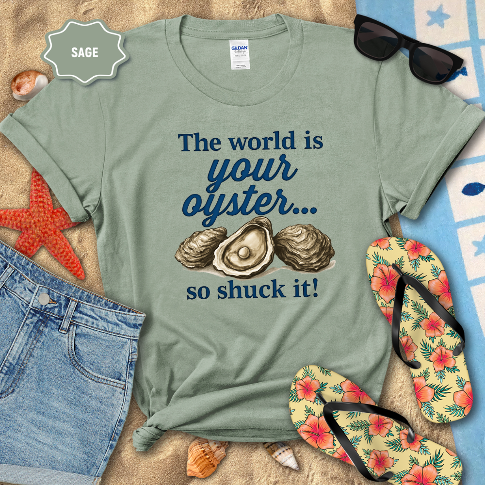 Sage green t-shirt with oyster graphic and text on a beach setting with sunglasses, flip-flops, and starfish.
