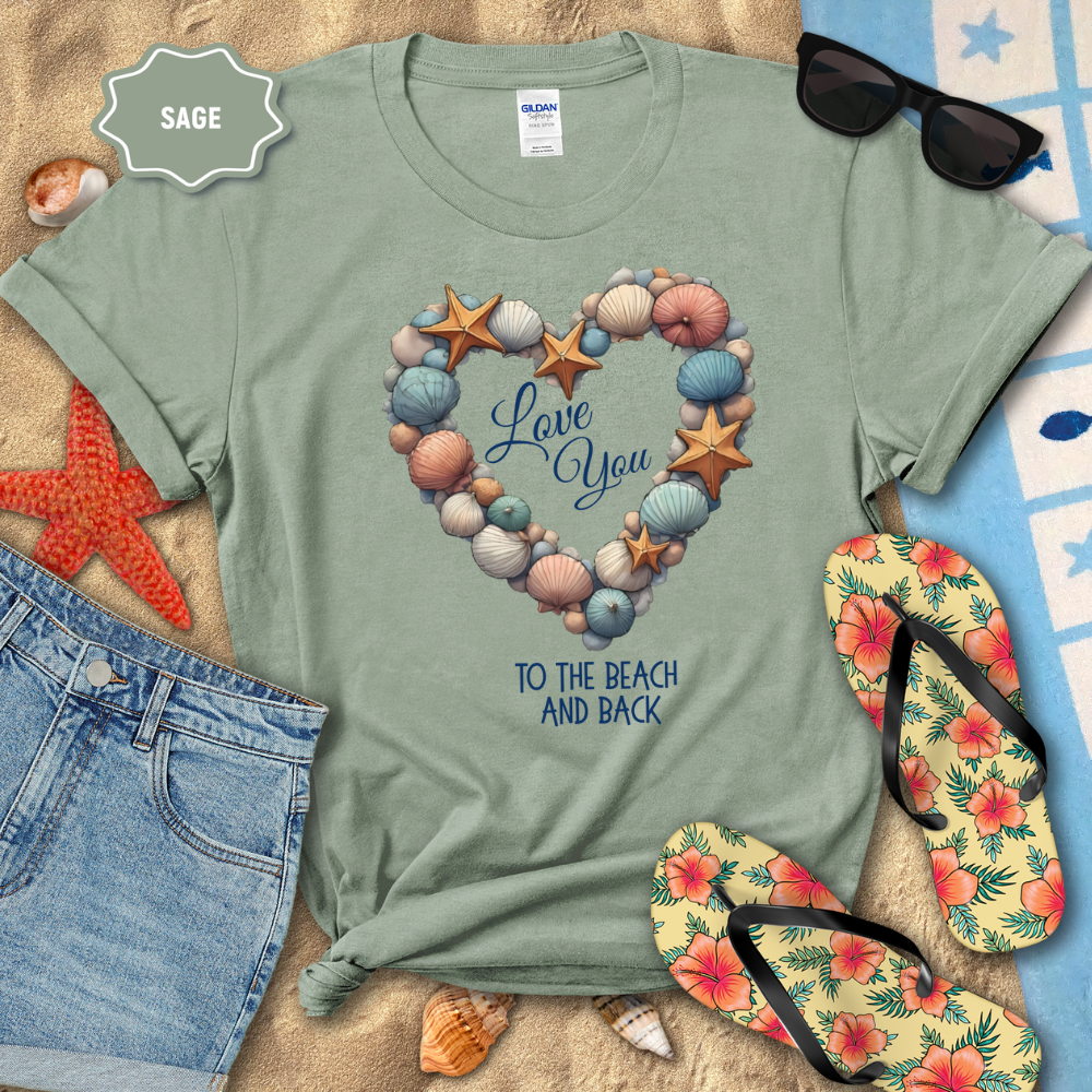 Sage green t-shirt with beach-themed design and accessories on a sandy background