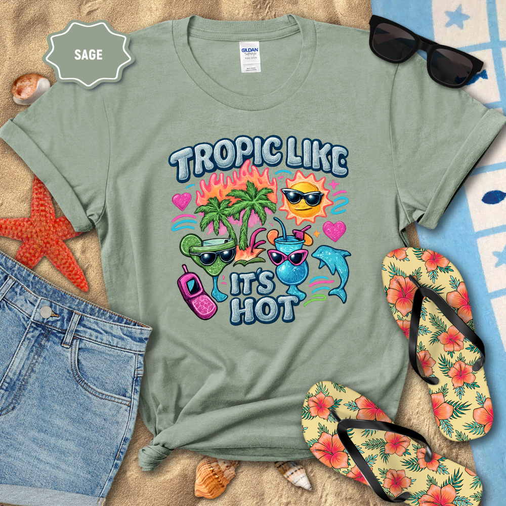 Sage green t-shirt with tropical-themed design on a beach setting with sunglasses, flip-flops, and starfish.