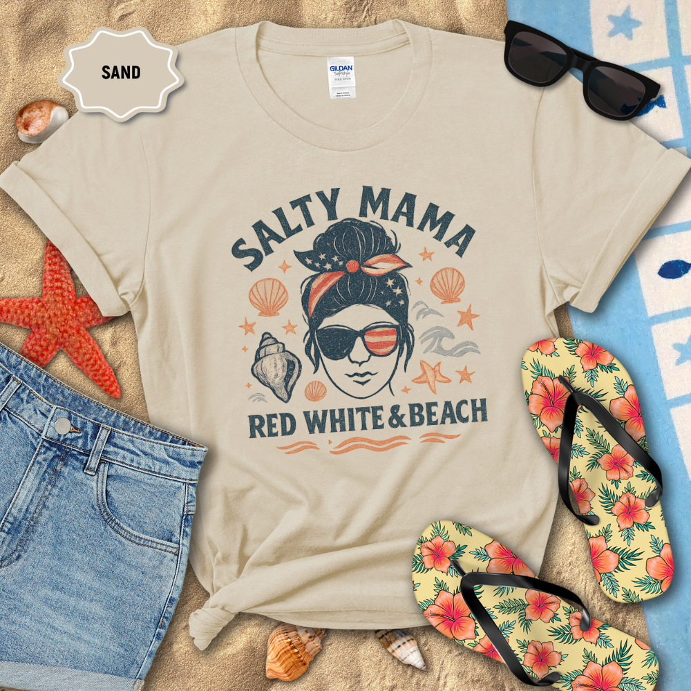 Beige t-shirt with 'Salty Mama Red White & Beach' design on sand with sunglasses, flip-flops, and beach accessories.