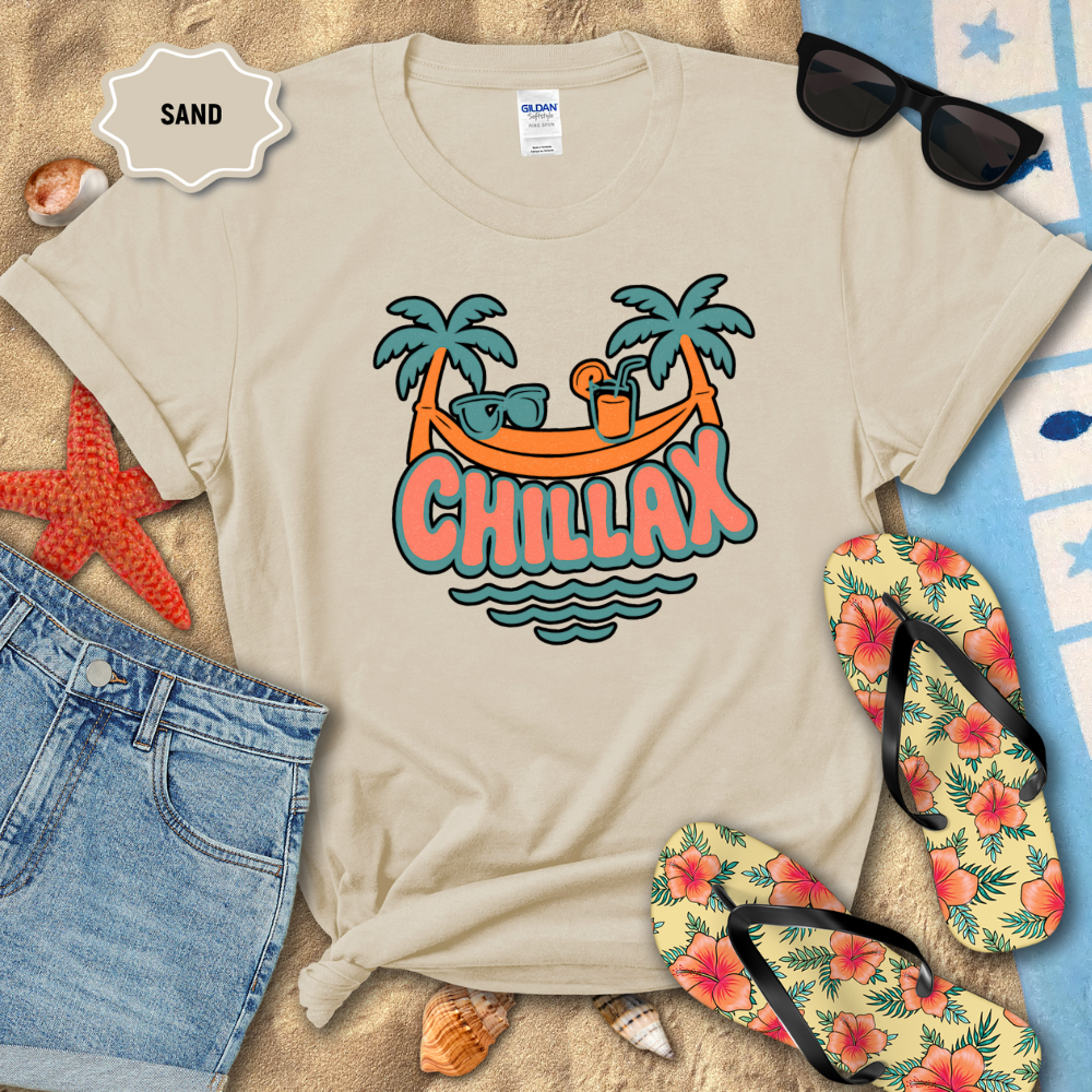 Beige t-shirt with 'Chillax' design on a sandy background with beach accessories.