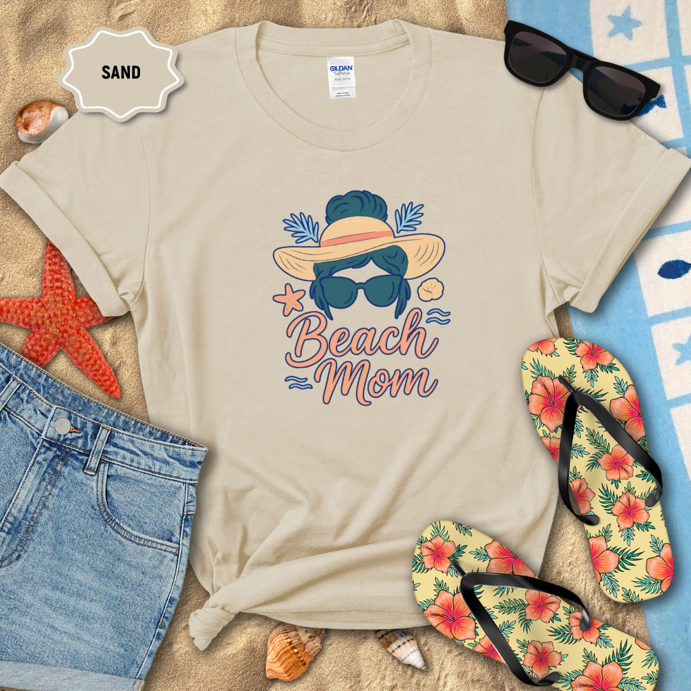 Beige t-shirt with 'Beach Mom' design on sand with beach accessories.