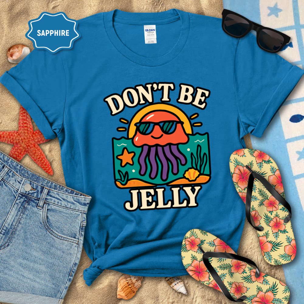 Blue t-shirt with 'Don't Be Jelly' design on a beach setting with sunglasses, flip-flops, and starfish.