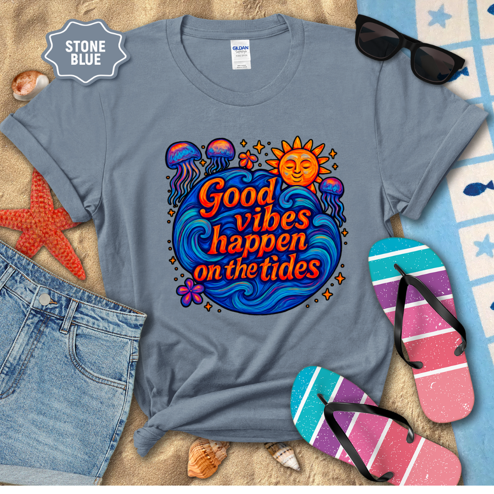 Stone blue t-shirt with 'Good vibes happen on the tides' design, sunglasses, denim shorts, and flip-flops on a sandy background.