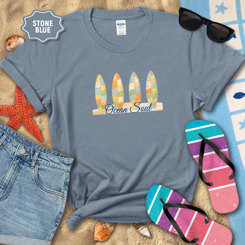 Stone blue t-shirt with 'Ocean Soul' design on a sandy background with beach accessories.