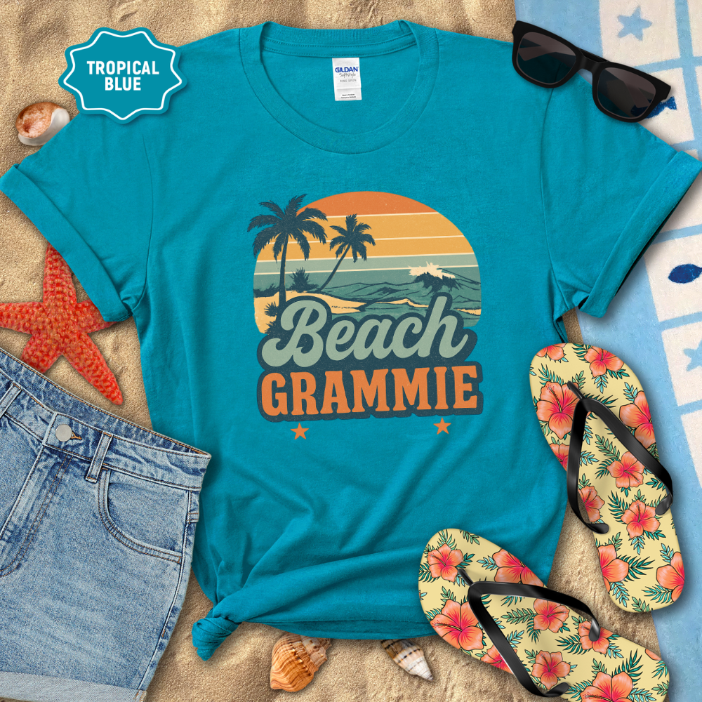 Blue t-shirt with 'Beach Grammie' design on a sandy background with flip-flops and sunglasses.