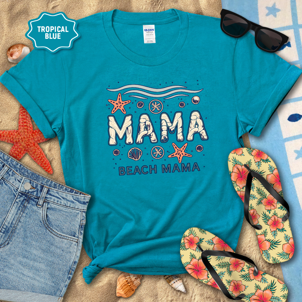 Blue t-shirt with 'Mama Beach Mama' text, sunglasses, flip-flops, and beach accessories on sand.