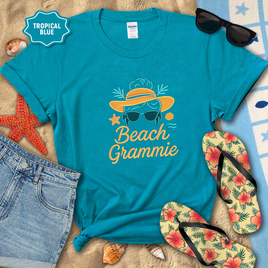 Blue t-shirt with 'Beach Grammie' design on a sandy background with flip-flops and sunglasses.