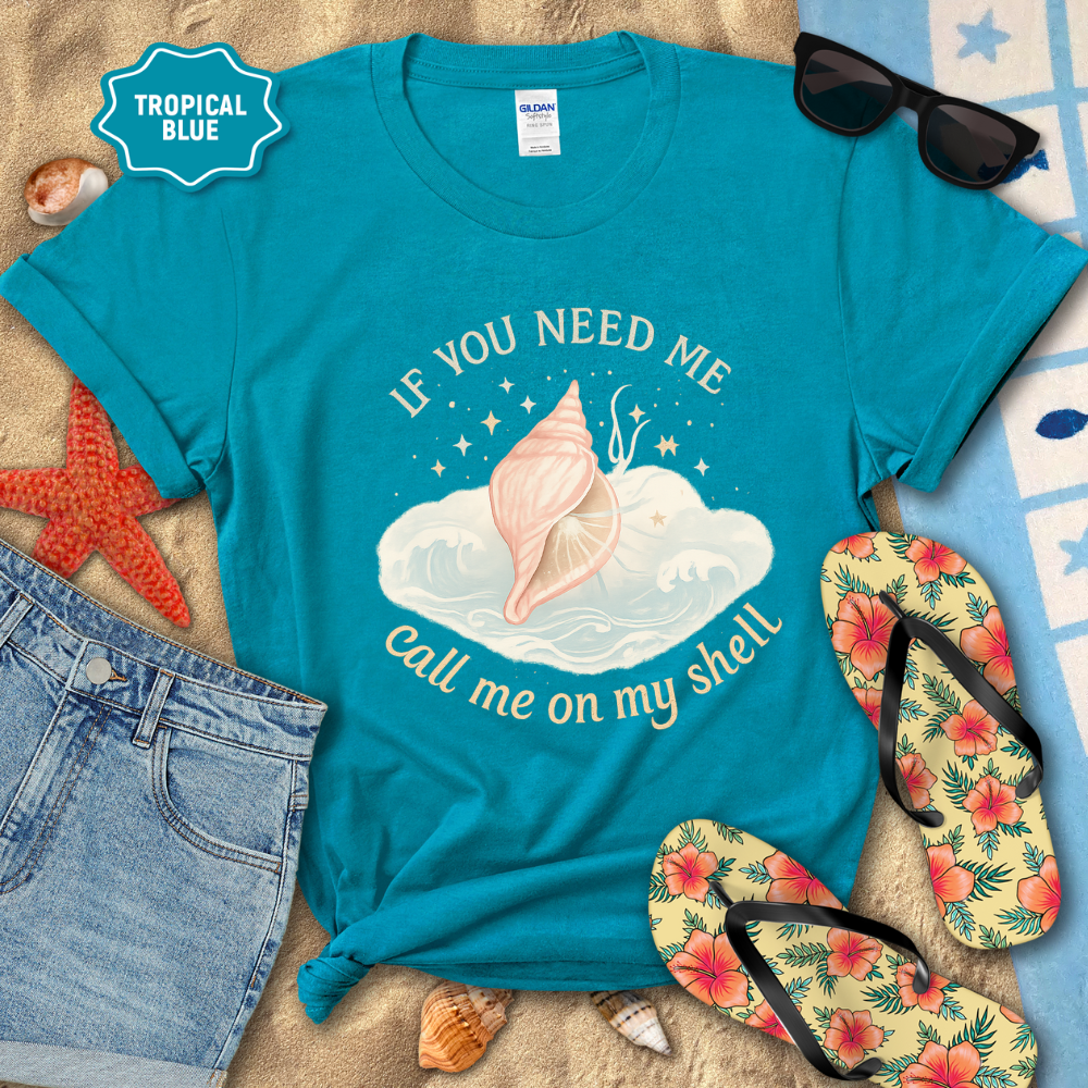 Blue t-shirt with shell graphic and text on a beach setting with sunglasses, flip-flops, and starfish.