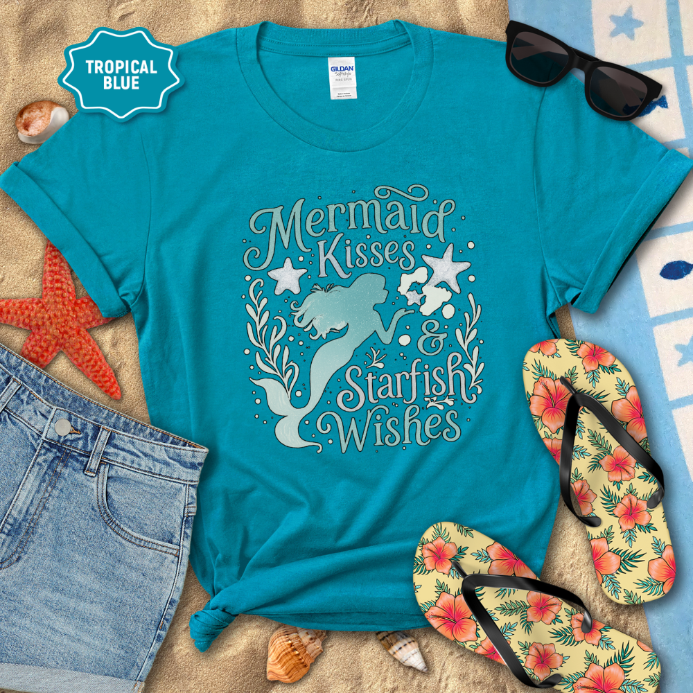 Turquoise t-shirt with 'Mermaid Kisses & Starfish Wishes' design on a beach-themed background.