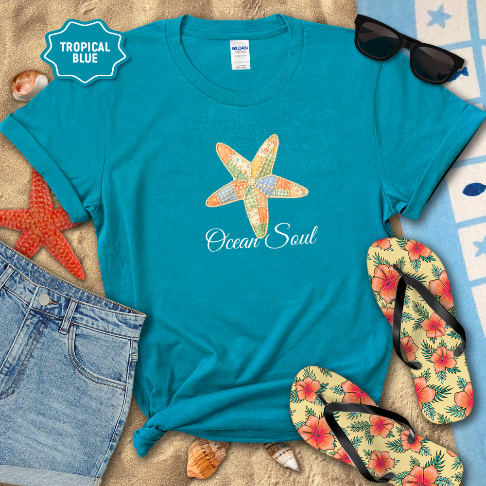 Turquoise t-shirt with starfish design and 'Ocean Soul' text, surrounded by beach accessories on sand.