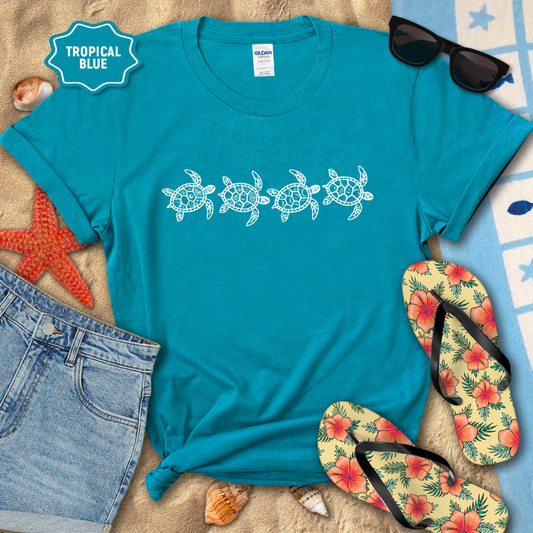 Blue t-shirt with turtle design, sunglasses, flip-flops, and beach accessories on a sandy background