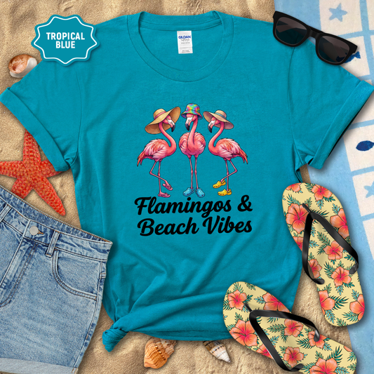 Blue t-shirt with flamingo design and 'Flamingos & Beach Vibes' text, surrounded by beach accessories.