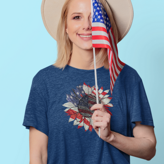 smiling woman in blue t-shirt with American flag sunflower design, holding U.S. flag

