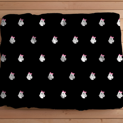 Black pillowcase with white ghost patterns and pink bows on a wooden surface