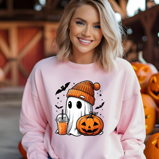 Woman wearing a pink sweatshirt with Halloween-themed design, surrounded by pumpkins.