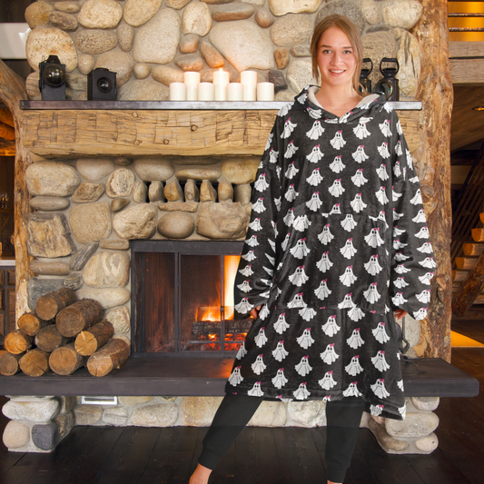 Person wearing a black hoodie with ghost patterns in front of a stone fireplace.