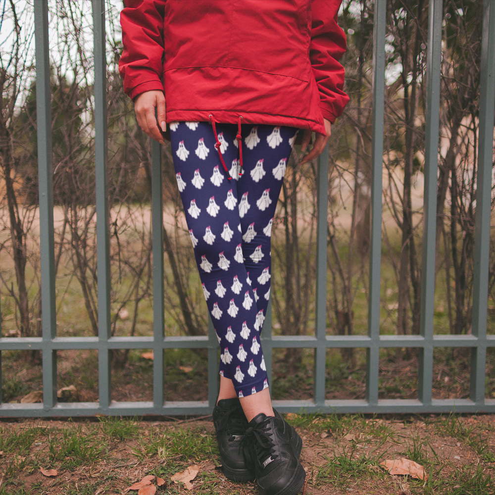 Person wearing a red jacket and blue leggings with white patterns, standing in front of a metal fence.