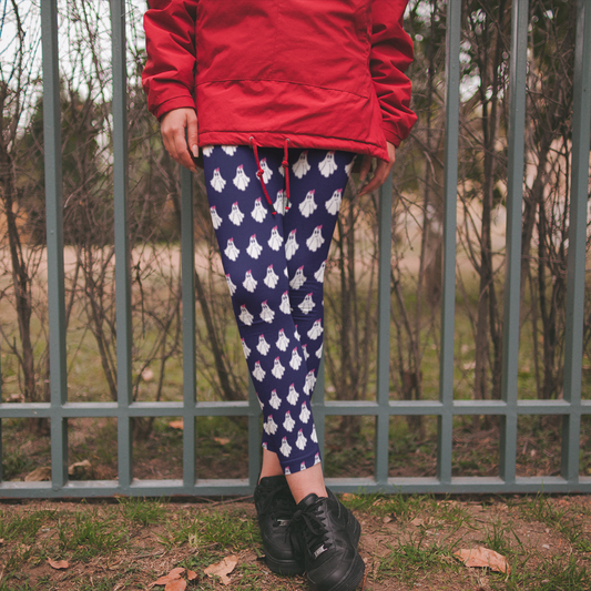 Person wearing a red jacket and blue leggings with white patterns, standing in front of a metal fence.