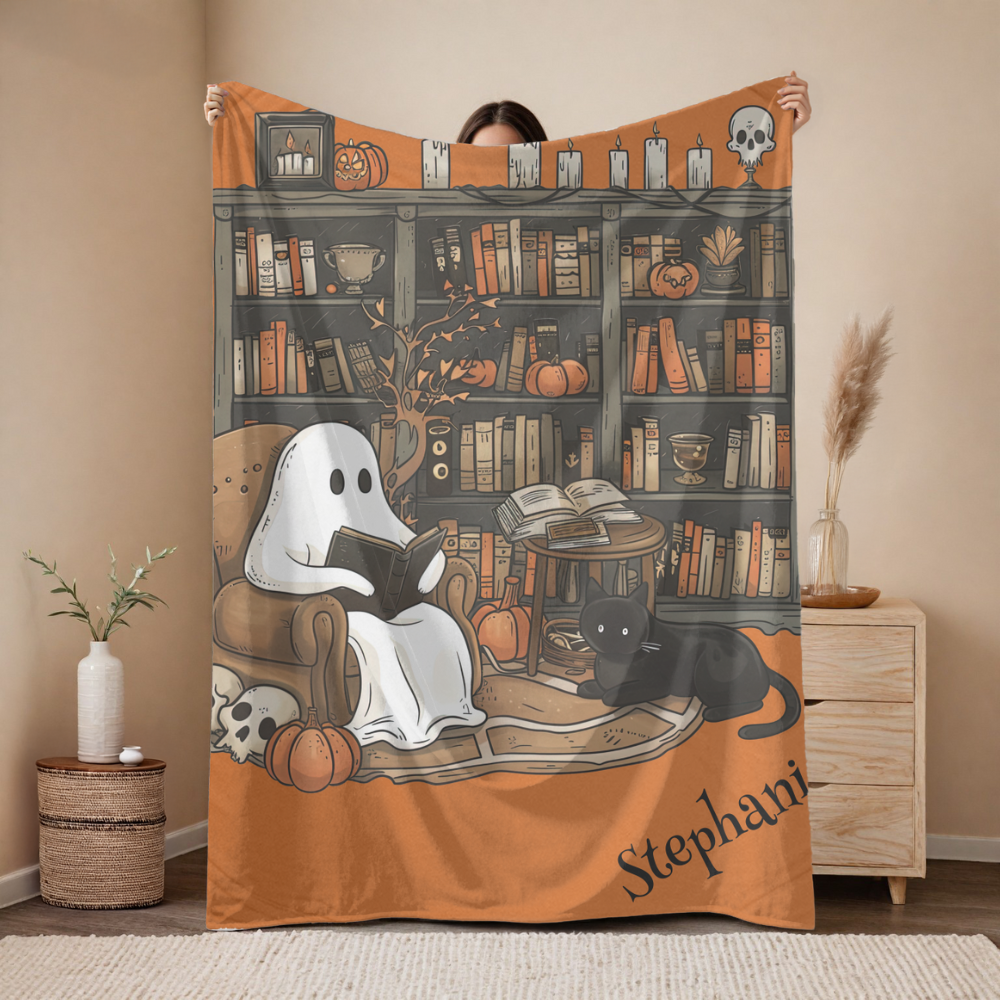 Person holding a Halloween-themed blanket with ghost, cat, and bookshelf design.