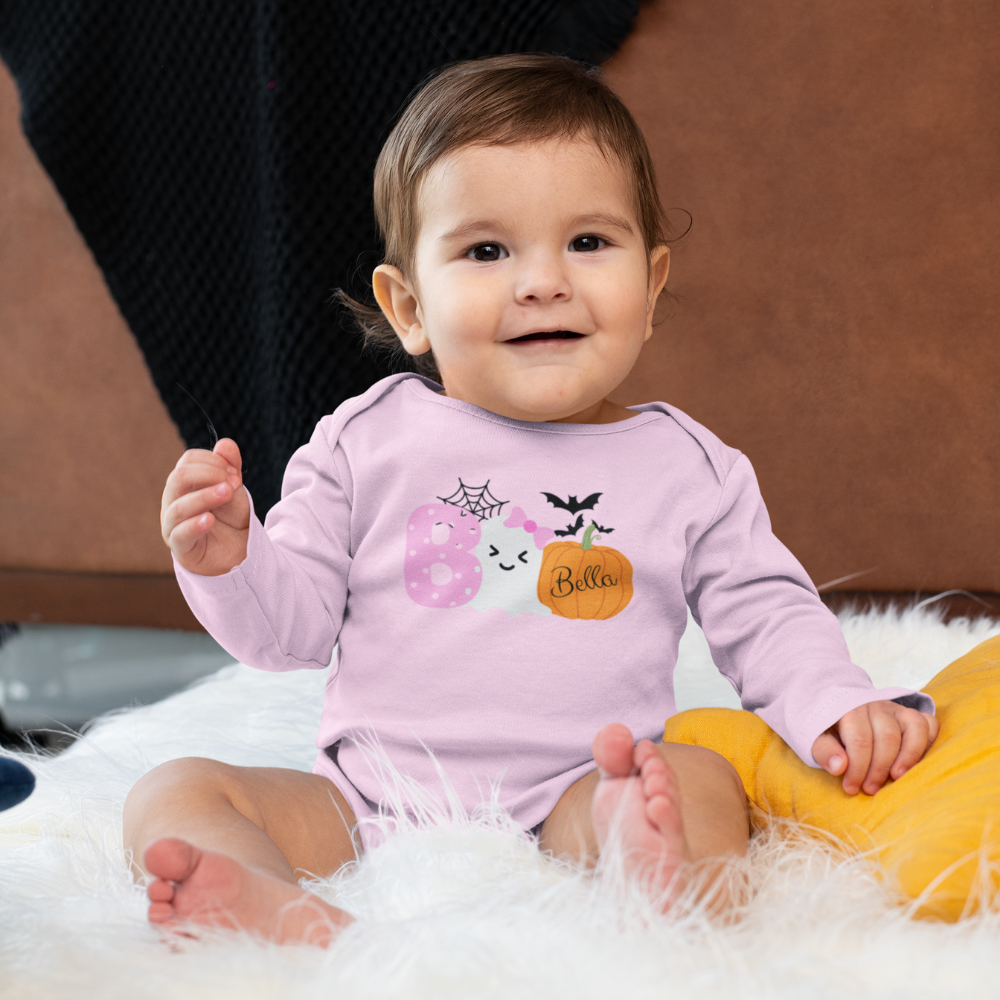 Baby wearing a pink Halloween-themed onesie sitting on a fluffy white surface.