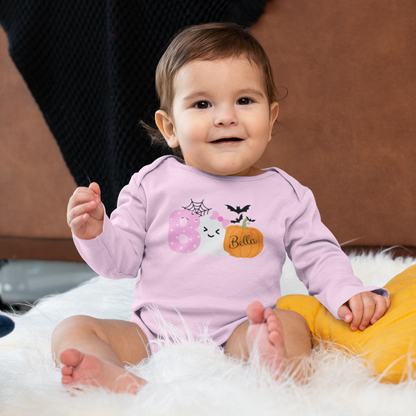 Baby wearing a pink Halloween-themed onesie sitting on a fluffy white surface.