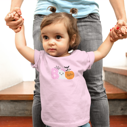 Child wearing a pink shirt with a Halloween design, standing between two adults.